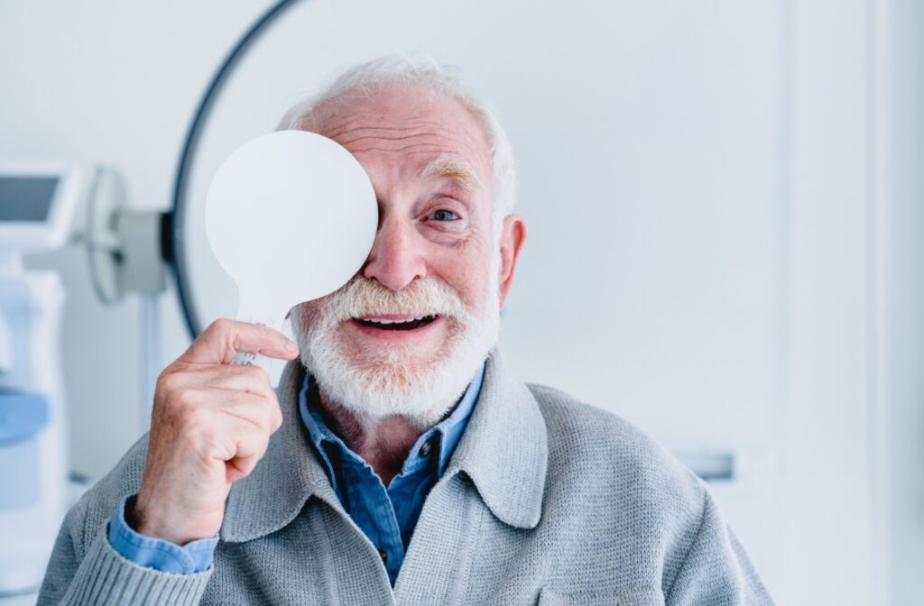 An older adult blocks vision with a paddle on one eye to test each eye's visual clarity separately.