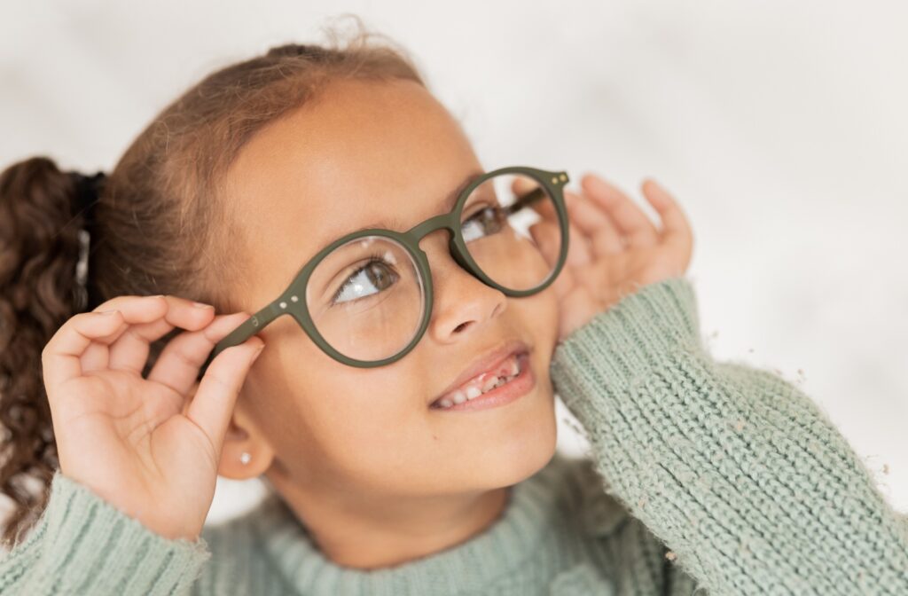 A child looks up while wearing a pair of green glasses