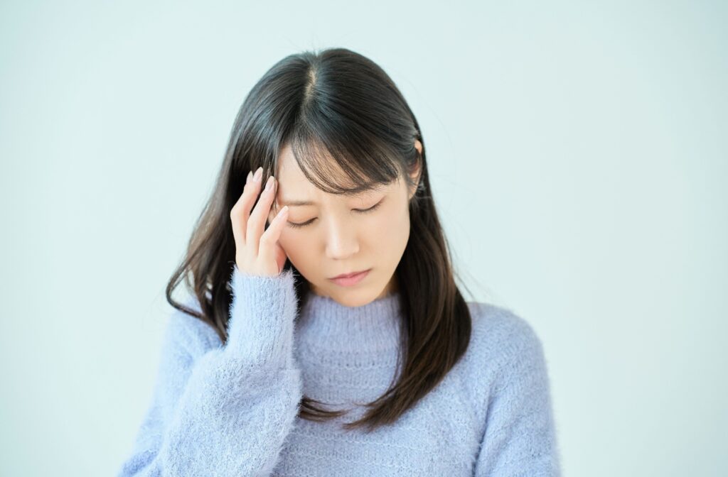 A woman in a blue sweater holds her head to help her dizziness